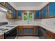 Kitchen boasts wood cabinets with unique blue accents, modern appliances, and a window view to the outdoors at 1024 Chalmers St, Durham, NC 27707