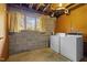 Basement laundry room with gray block walls, utility sink, and laundry machines at 1024 Chalmers St, Durham, NC 27707