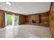 Living room featuring wood paneling, brick fireplace with shelving, and sliding glass door to the outside at 1024 Chalmers St, Durham, NC 27707