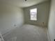 A bedroom under construction, featuring white walls and neutral floors, with a single hung window overlooking neighborhood homes at 1029 Mountain Crown St, Durham, NC 27703