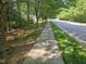 A sidewalk and road is lined with lush green trees offering a scenic view at 103 Trent Woods Way, Cary, NC 27519
