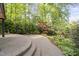 Backyard stone paver patio with stairs, leading to a beautifully landscaped yard with mature trees and shrubbery at 105 Bergeron Way, Cary, NC 27519