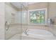 Bright bathroom featuring a soaking tub with tile surround and a glass enclosed shower at 105 Bergeron Way, Cary, NC 27519