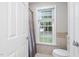 Bathroom featuring neutral tile surround, a window with a wooded view, and a shower curtain at 105 Bergeron Way, Cary, NC 27519