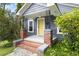 Close-up of a home's entrance, featuring a yellow door, brick-lined porch, and decorative black iron railings at 107 E Hammond St, Durham, NC 27704
