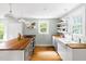 Sunlit kitchen featuring a butcher block countertop, stainless steel appliances, and white cabinetry at 107 E Hammond St, Durham, NC 27704