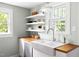 This kitchen offers a farmhouse sink, butcher block countertop, and floating shelves at 107 E Hammond St, Durham, NC 27704