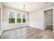 Bright dining room with large windows and modern lighting, complemented by stylish wall paneling and gray wood-look flooring at 1112 Valley Rose Way, Durham, NC 27712