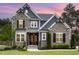 Charming two-story home at sunset featuring a stone facade, gray siding, wood accents, and a manicured front yard at 1112 Valley Rose Way, Durham, NC 27712