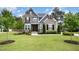 Beautiful two-story home with stone and gray siding, complemented by a lush green lawn and manicured landscaping at 1112 Valley Rose Way, Durham, NC 27712