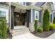 Inviting front porch with stone steps, wood columns, a charming light fixture, and manicured landscaping at 1112 Valley Rose Way, Durham, NC 27712