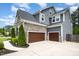 Spacious two-car garage with carriage doors, stone accents, and gray siding, complemented by lush landscaping at 1112 Valley Rose Way, Durham, NC 27712
