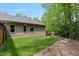 Spacious backyard with lush green grass, three windows, and mulch with trees providing shade at 120 Wood Lake Dr, Fuquay Varina, NC 27526