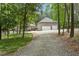 Gravel driveway leading to a spacious three-car garage and a brick home nestled in the woods at 120 Wood Lake Dr, Fuquay Varina, NC 27526