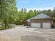 Spacious three-car garage with brick exterior and a gravel driveway, offering ample parking at 120 Wood Lake Dr, Fuquay Varina, NC 27526