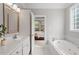 Bathroom featuring a white bathtub, a dual sink vanity, and a doorway view to the bedroom at 121 Cobblepoint Way, Holly Springs, NC 27540