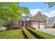 Beautiful brick home featuring an attached garage, manicured shrubs, and green lawn at 121 Cobblepoint Way, Holly Springs, NC 27540