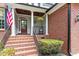 Inviting front porch with brick steps and detailed columns, creating a warm entry at 121 Cobblepoint Way, Holly Springs, NC 27540