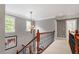 Upstairs hallway featuring elegant lighting, wood railing, and neutral walls at 121 Cobblepoint Way, Holly Springs, NC 27540
