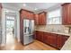 Traditional kitchen featuring wooden cabinets, granite counters, stainless steel fridge, and hardwood floors at 121 Cobblepoint Way, Holly Springs, NC 27540