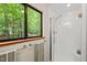 This bright bathroom features a glass shower with a built-in seat and a large window with nature views at 1213 Blackwood Mountain Rd, Chapel Hill, NC 27516