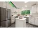 Modern kitchen features white cabinets, stainless steel appliances, an island, and a view of the forest at 1213 Blackwood Mountain Rd, Chapel Hill, NC 27516