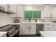 Modern kitchen features white cabinets, stainless steel appliances, and a large window with views of the woods at 1213 Blackwood Mountain Rd, Chapel Hill, NC 27516