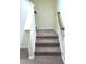 Carpeted staircase provides access to the next level, featuring white risers and wooden handrail at 1240 Grenshaw Dr, Morrisville, NC 27560