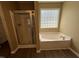 Bathroom featuring glass shower, soaking tub and natural light from block window at 125 Occidental Dr, Holly Springs, NC 27540