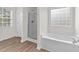 Bathroom featuring a glass-enclosed shower, garden tub, and window with a view at 125 Occidental Dr, Holly Springs, NC 27540