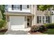 Two-story home featuring beige siding, black shutters, an attached garage, and landscaped front yard at 125 Occidental Dr, Holly Springs, NC 27540
