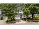 Two-story home with beige siding, black shutters, garage, manicured landscaping, and mature shade trees at 125 Occidental Dr, Holly Springs, NC 27540