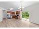Open kitchen with stainless steel appliances, wood cabinets, modern chandelier and sliding glass doors to patio at 125 Occidental Dr, Holly Springs, NC 27540