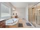 Bright bathroom featuring a soaking tub under a window, and a glass-enclosed shower at 1632 Ferntree Ct, Morrisville, NC 27560