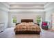 A large bedroom with tray ceiling and large windows, plus an accent chair at 1632 Ferntree Ct, Morrisville, NC 27560