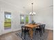 Bright dining area with a wooden table, black chairs, modern chandelier and access to the outdoor balcony and view at 1824 Amberly Ledge Way, Cary, NC 27519
