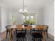 Bright dining area with a wooden table, black chairs, modern chandelier, and access to the outdoor deck at 1824 Amberly Ledge Way, Cary, NC 27519