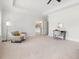 Primary bedroom featuring a seating area, tray ceiling, and an open doorway to the ensuite bathroom at 1824 Amberly Ledge Way, Cary, NC 27519