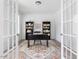 Well-lit home office with French doors, neutral walls, large rug, and built-in bookshelves at 1824 Amberly Ledge Way, Cary, NC 27519