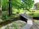 Backyard stream with a charming wooden bridge and steps surrounded by lush greenery; creating a tranquil retreat at 1846 Forest Wood Rd, Rocky Mount, NC 27804