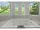 Jetted tub with tile surround and three windows overlooking a wooded view at 205 Glenview Pl, Chapel Hill, NC 27514