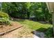 Expansive backyard with a lush lawn, mature trees, and a variety of garden beds and retaining walls at 210 Needle Park Dr, Cary, NC 27513