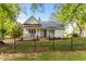 Charming white home with a black metal roof, front porch, and wrought iron fence at 2102 Courtland Dr, Sanford, NC 27330
