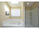 Well-lit bathroom featuring a skylight, soaking tub, and glass-enclosed shower at 221 Ironwoods Dr, Chapel Hill, NC 27516