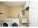 Bright laundry room equipped with modern washer and dryer, utility sink, and storage space at 221 Ironwoods Dr, Chapel Hill, NC 27516