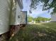Side of the home showing siding and brick foundation surrounded by large grassy yard undergoing renovations at 249 Finley Ct, Clayton, NC 27520