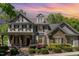 Charming two-story home with a stone facade, covered porch, and manicured landscaping under a colorful sunset at 2821 Penfold Ln, Wake Forest, NC 27587