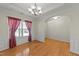 Bright dining room featuring hardwood floors, elegant chandelier, and large window with stylish curtains at 3212 Imperial Oaks Dr, Raleigh, NC 27614