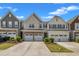 Street view of townhomes featuring two-car garages and well-maintained landscaping under a clear, sunny sky at 4137 Lofty Ridge Pl, Morrisville, NC 27560
