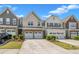 Attractive townhomes featuring two-car garages and manicured front landscaping under a sunny sky at 4137 Lofty Ridge Pl, Morrisville, NC 27560